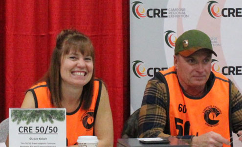 Two smiling volunteers siting at a 50/50 raffle table 
